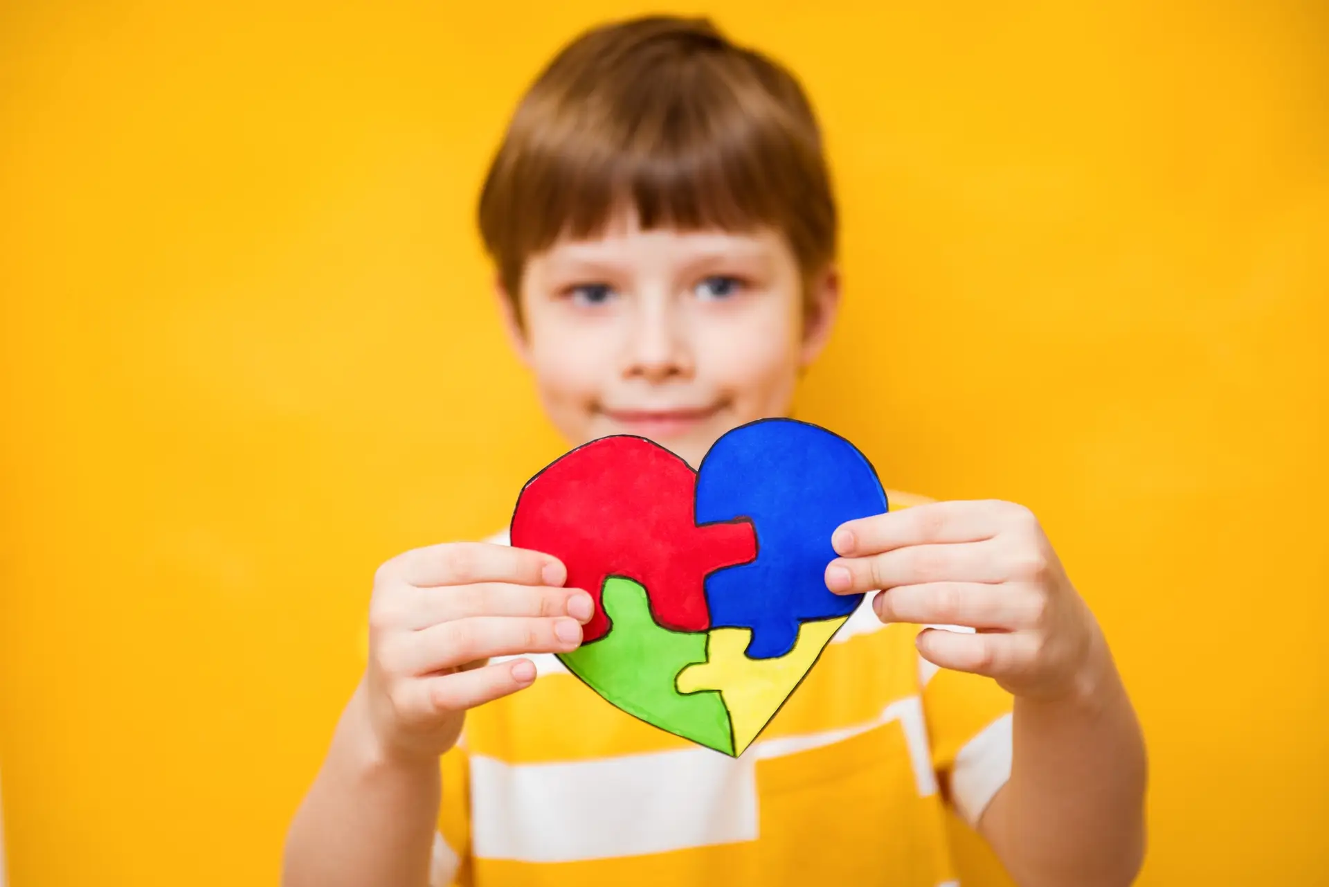 Kid boy hands holding puzzle heart, child mental health concept, world autism awareness day